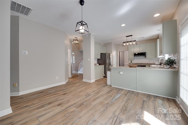 kitchen with stainless steel appliances, light wood-type flooring, baseboards, a peninsula, and recessed lighting