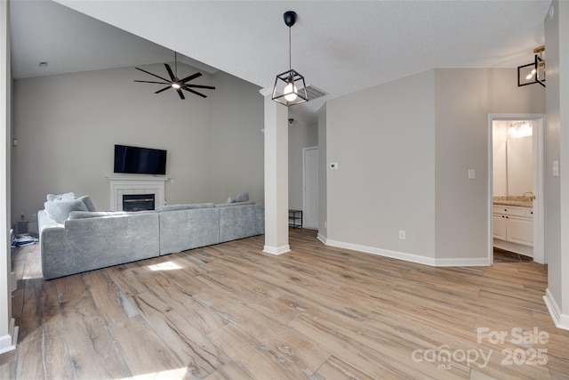 unfurnished living room with light wood-style floors, a ceiling fan, baseboards, a tiled fireplace, and high vaulted ceiling
