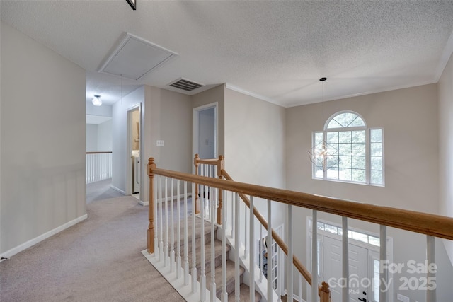 hallway featuring attic access, an upstairs landing, a textured ceiling, light carpet, and baseboards