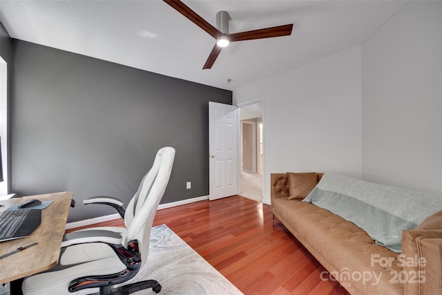 home office featuring wood finished floors, a ceiling fan, and baseboards