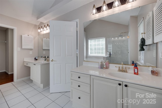 full bath featuring lofted ceiling, a shower stall, tile patterned flooring, two vanities, and baseboards