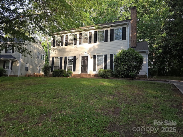 colonial inspired home with a chimney and a front lawn