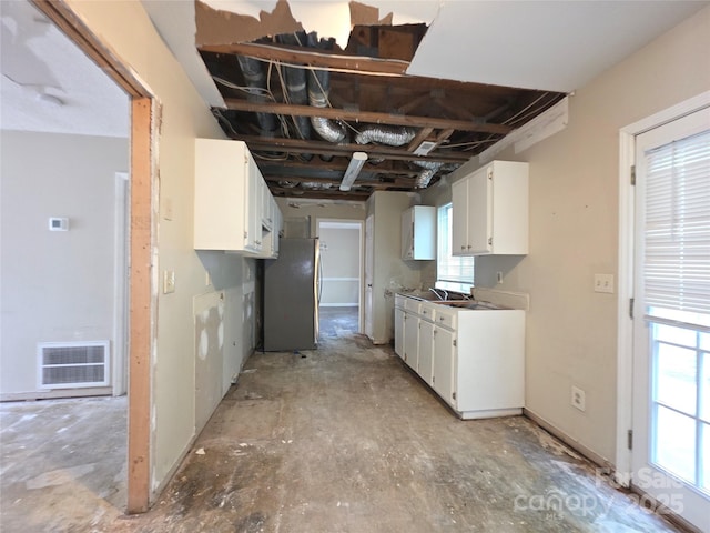 kitchen with freestanding refrigerator, white cabinetry, healthy amount of natural light, and a sink
