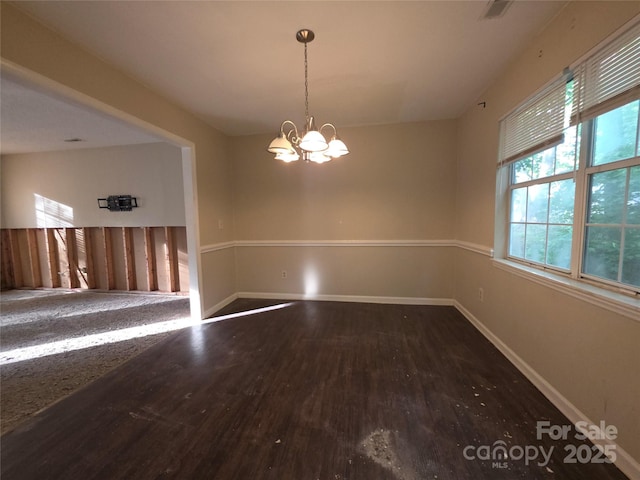 unfurnished dining area with wood finished floors, a chandelier, and baseboards