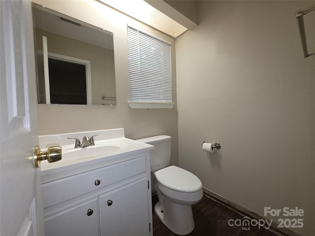 bathroom featuring toilet, vanity, and wood finished floors