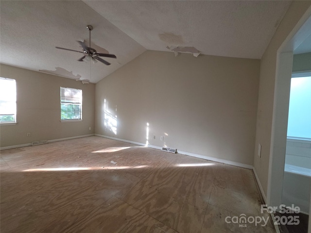 unfurnished room with ceiling fan, a textured ceiling, vaulted ceiling, and baseboards