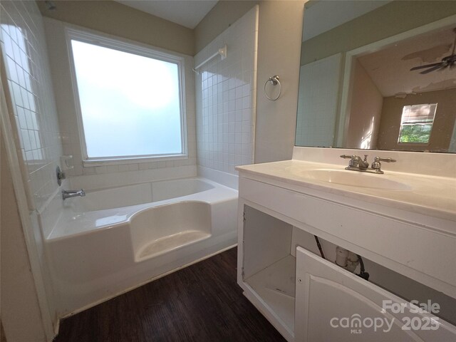 full bath featuring a tub, wood finished floors, and vanity