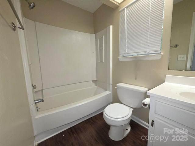 bathroom with wood finished floors, toilet, vanity, shower / washtub combination, and baseboards