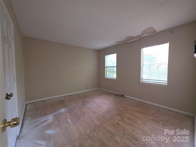 spare room featuring baseboards and a textured ceiling