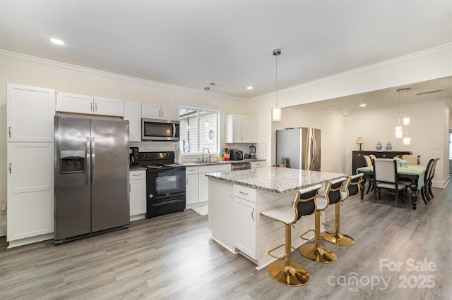 131 Swink St SW, Concord, NC 28027 - kitchen with appliances with stainless steel finishes, a sink, a kitchen bar, light wood-type flooring, and crown molding