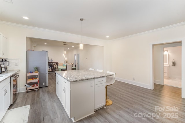 131 Swink St SW, Concord, NC 28027 - kitchen with stainless steel appliances, ornamental molding, light wood-style floors, white cabinetry, and a center island