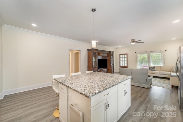 131 Swink St SW, Concord, NC 28027 - kitchen featuring ceiling fan, a kitchen island, open floor plan, light wood-style flooring, and crown molding