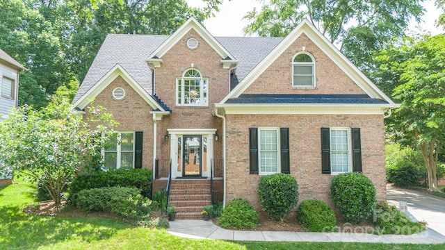 view of front of house featuring brick siding and roof with shingles