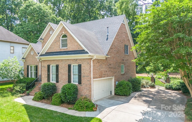 view of front facade with concrete driveway, a shingled roof, brick siding, an attached garage, and a front yard