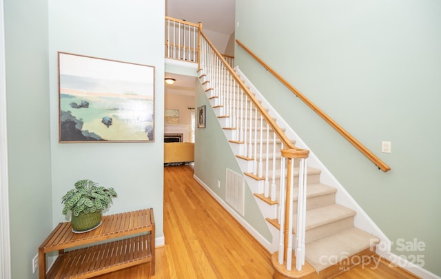 stairs with wood finished floors and a fireplace