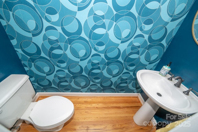 bathroom with toilet, a sink, and wallpapered walls