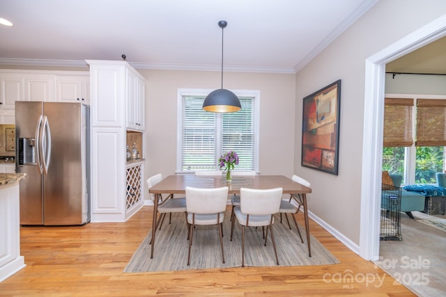 dining space featuring light wood-type flooring, baseboards, and crown molding