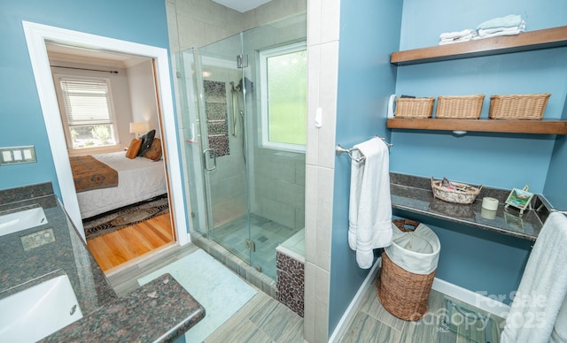 ensuite bathroom with a shower stall, double vanity, and baseboards