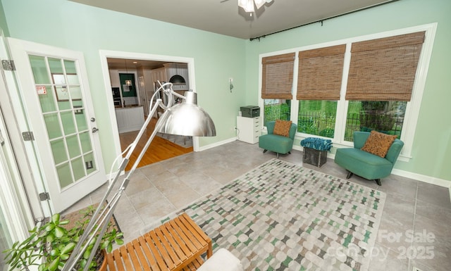 sitting room featuring ceiling fan, tile patterned flooring, and baseboards