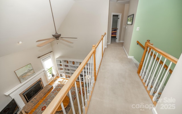 corridor with an upstairs landing, vaulted ceiling, and baseboards