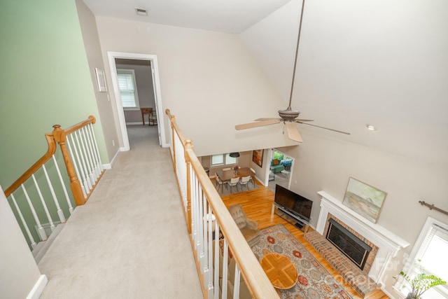 hallway with an upstairs landing, lofted ceiling, and baseboards