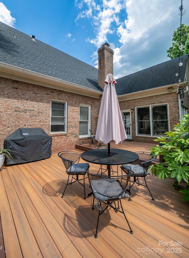 wooden terrace featuring outdoor dining space and area for grilling