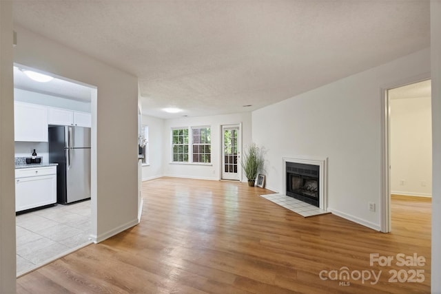 6016 Gray Gate Ln Unit C, Charlotte, NC 28210 - unfurnished living room with light wood-style floors, a tile fireplace, and baseboards