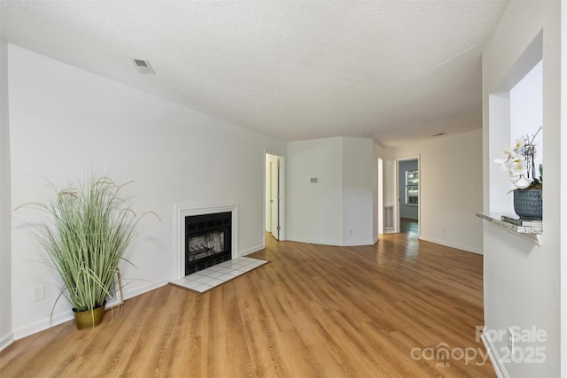 6016 Gray Gate Ln Unit C, Charlotte, NC 28210 - unfurnished living room featuring light wood-style flooring, a fireplace, baseboards, and a textured ceiling
