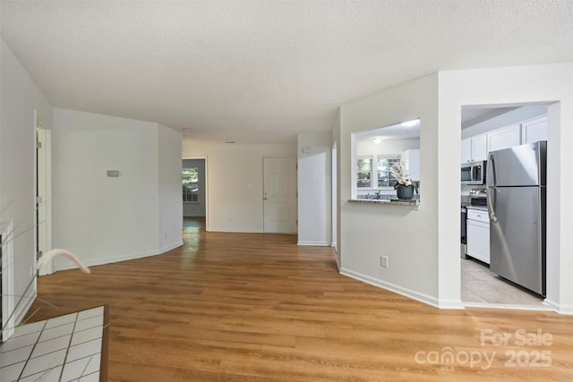 6016 Gray Gate Ln Unit C, Charlotte, NC 28210 - unfurnished living room with light wood-style flooring, baseboards, and a textured ceiling