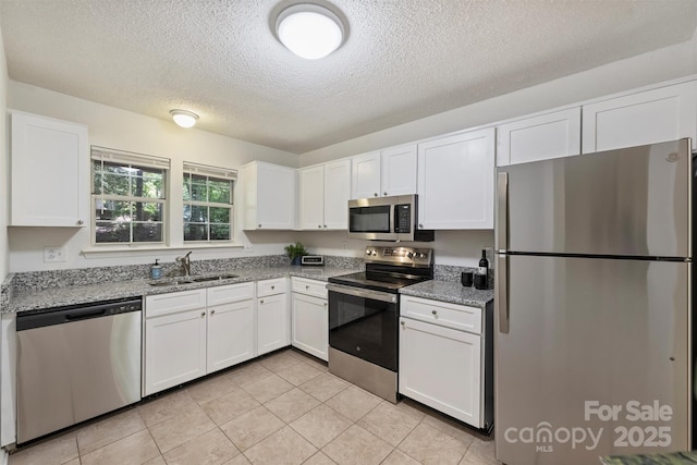 6016 Gray Gate Ln Unit C, Charlotte, NC 28210 - kitchen featuring stainless steel appliances, a sink, white cabinets, a textured ceiling, and light stone counters