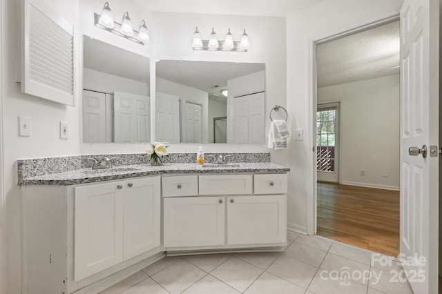 6016 Gray Gate Ln Unit C, Charlotte, NC 28210 - bathroom with double vanity, tile patterned floors, baseboards, and a textured ceiling