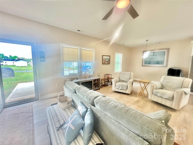 living room with baseboards, light wood finished floors, and ceiling fan