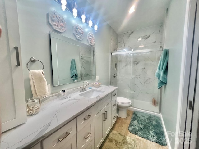 full bathroom featuring a marble finish shower, toilet, wood finished floors, and vanity