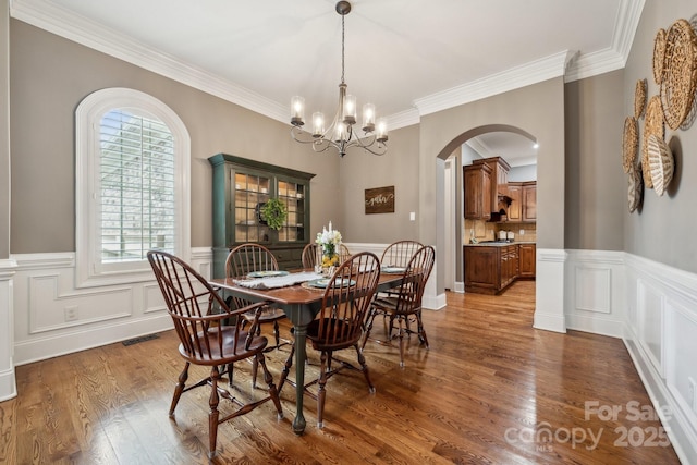 309 Palm Cove Way, York, SC 29745 - dining space with a chandelier, arched walkways, crown molding, wood finished floors, and wainscoting