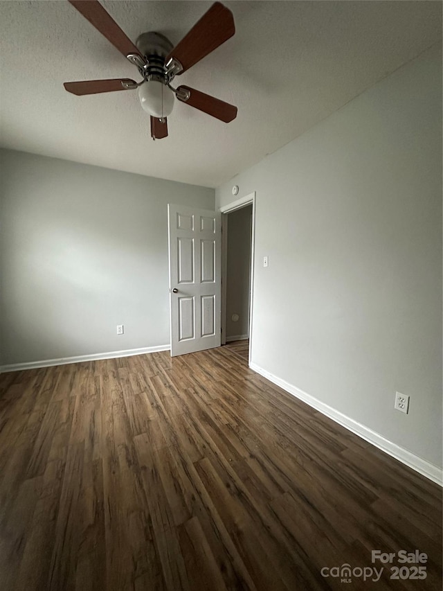 empty room with dark wood-type flooring, baseboards, and a ceiling fan