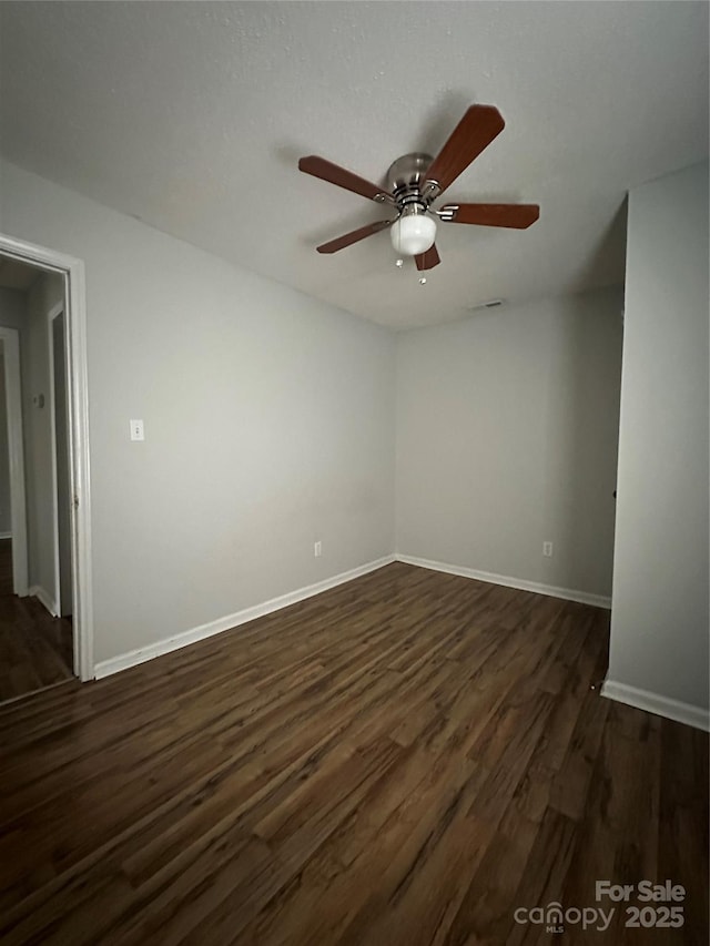unfurnished room with a ceiling fan, dark wood-style floors, and baseboards