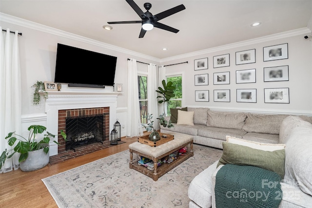 living room featuring a ceiling fan, crown molding, wood finished floors, a fireplace, and recessed lighting