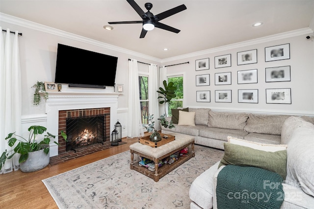 living room featuring ceiling fan, crown molding, a fireplace, wood finished floors, and recessed lighting