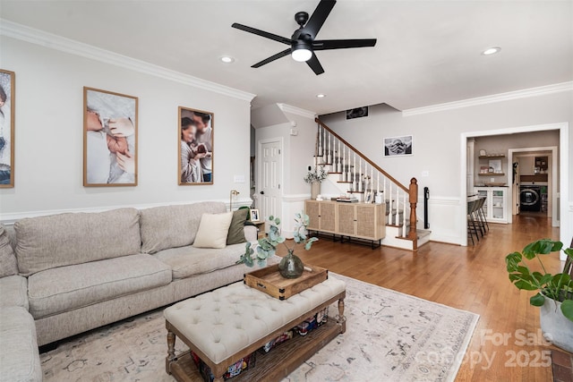 living area featuring crown molding, washer / clothes dryer, stairs, a ceiling fan, and wood finished floors