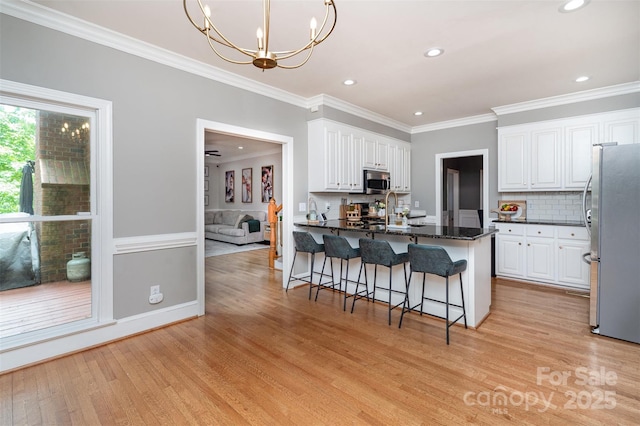 kitchen with appliances with stainless steel finishes, light wood-style floors, white cabinets, crown molding, and recessed lighting