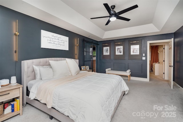 bedroom with carpet flooring, a raised ceiling, a ceiling fan, and baseboards