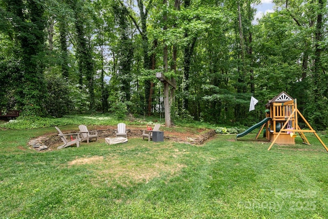view of grassy yard with a playground and a fire pit