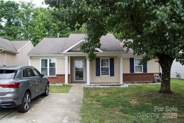view of front of home featuring brick siding, a front yard, roof with shingles, and covered porch