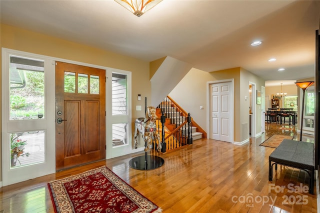 entryway with wood-type flooring, stairs, a chandelier, recessed lighting, and baseboards