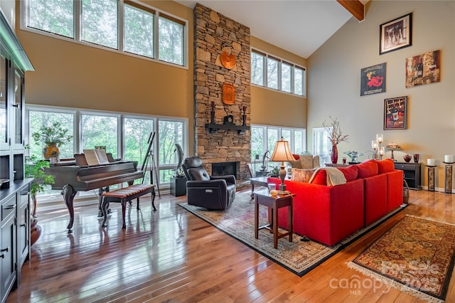 living area featuring high vaulted ceiling, wood-type flooring, beam ceiling, and a fireplace