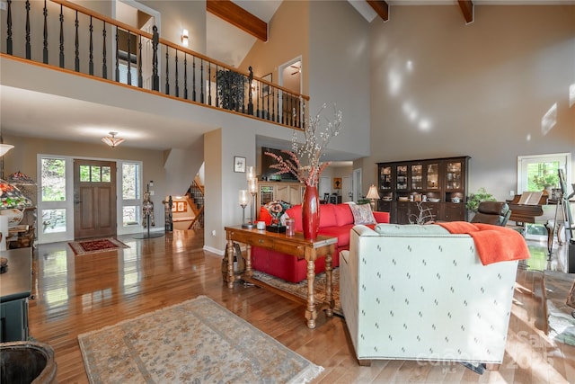 living room featuring stairway, high vaulted ceiling, beamed ceiling, wood finished floors, and baseboards