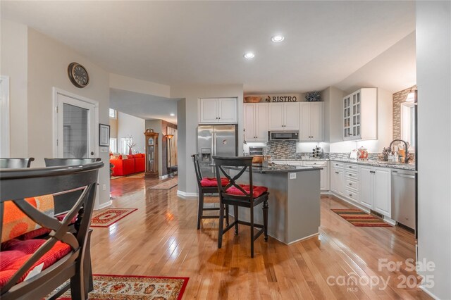 kitchen featuring stainless steel appliances, white cabinetry, light wood finished floors, a breakfast bar area, and recessed lighting
