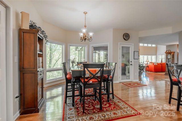dining room featuring light wood-style floors, a chandelier, and baseboards