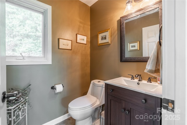 half bathroom with toilet, vanity, and baseboards