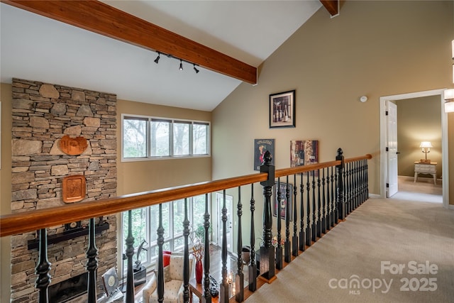 corridor with beam ceiling, high vaulted ceiling, carpet, baseboards, and track lighting